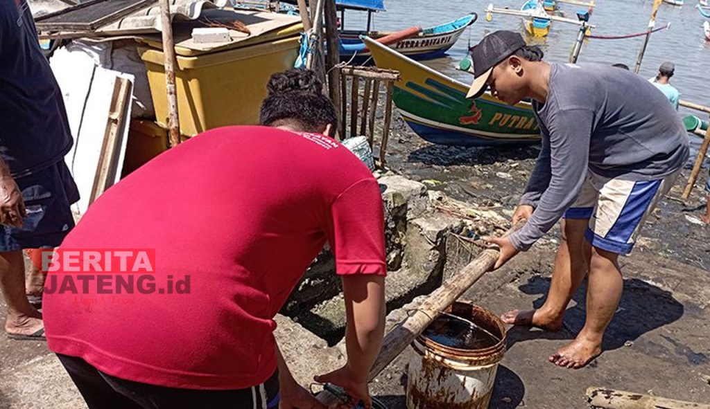Warga setempat mengangkut tumpahan minyak yang mereka kumpulkan dari perairan Cilacap, Selasa (28/06). (Antara/Beritajateng.id)