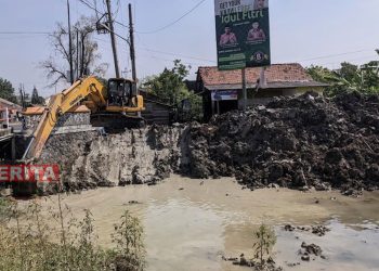 Alat berat yang digunakan untuk mengeruk sedimentasi saluran irigasi Klambu Kiri. (Tomi Budianto/Koran Lingkar)
